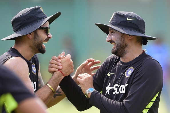 Virat Kohli (L) and Harbhajan Singh (R) share a light monent during a practice session. Photo credit- MUNIR UZ ZAMAN/AFP via Getty Images