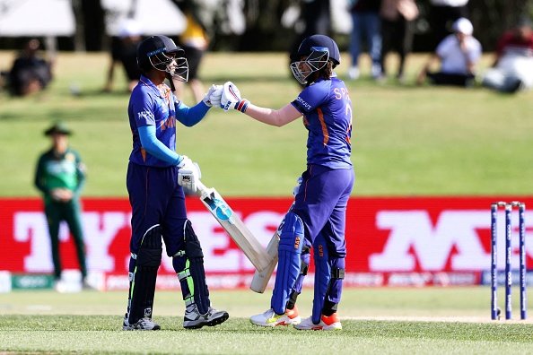 India's Pooja Vastrakar (L) and Sneh Rana bump gloves during the Round 1 Women's Cricket World cup match between India and Pakistan at Bay Oval in Tauranga on March 6, 2022. (Photo by MICHAEL BRADLEY / AFP) (Photo by MICHAEL BRADLEY/AFP via Getty Images)